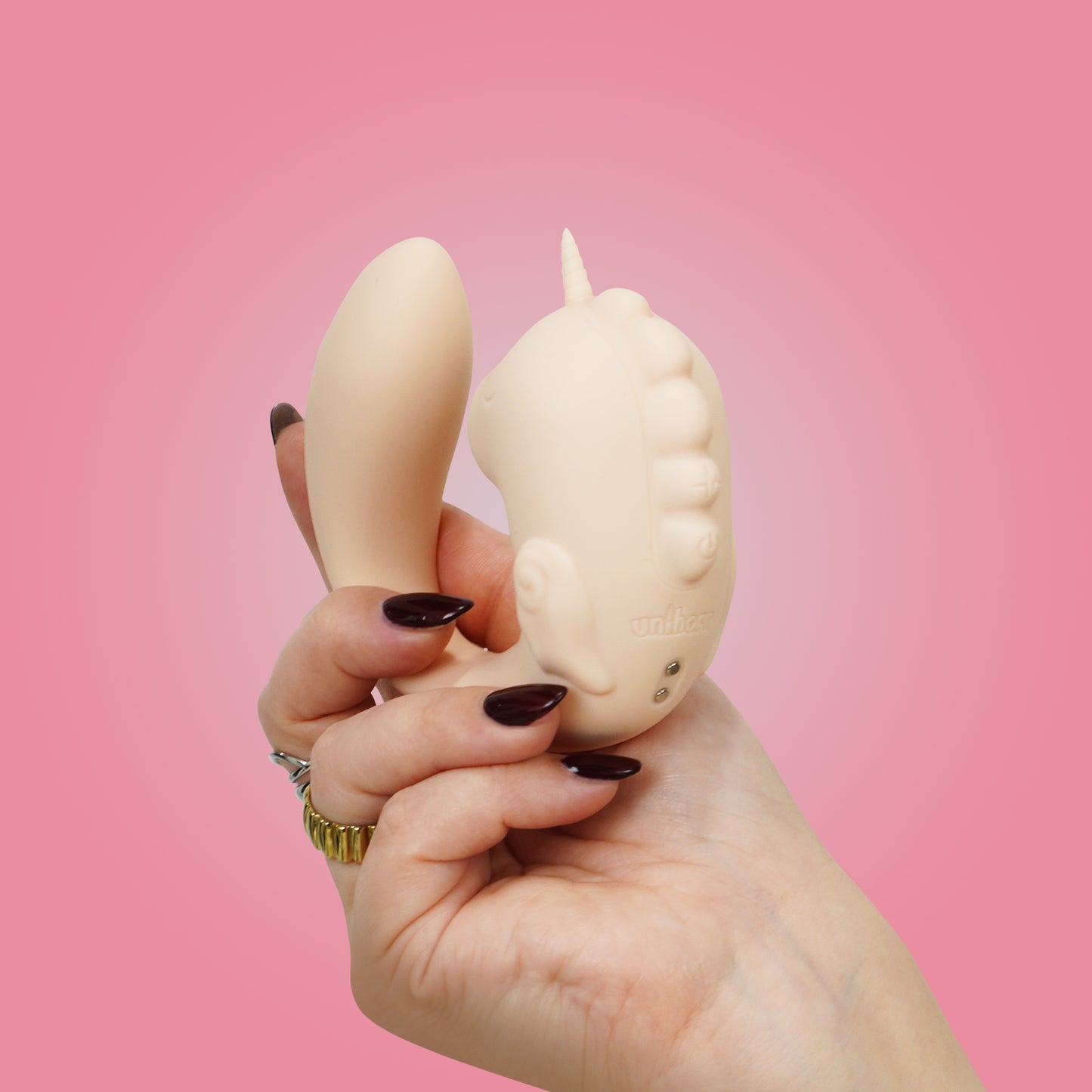 Coral Throb Unihorn C-Horse back in natural c-shaped position in hand on a pink background