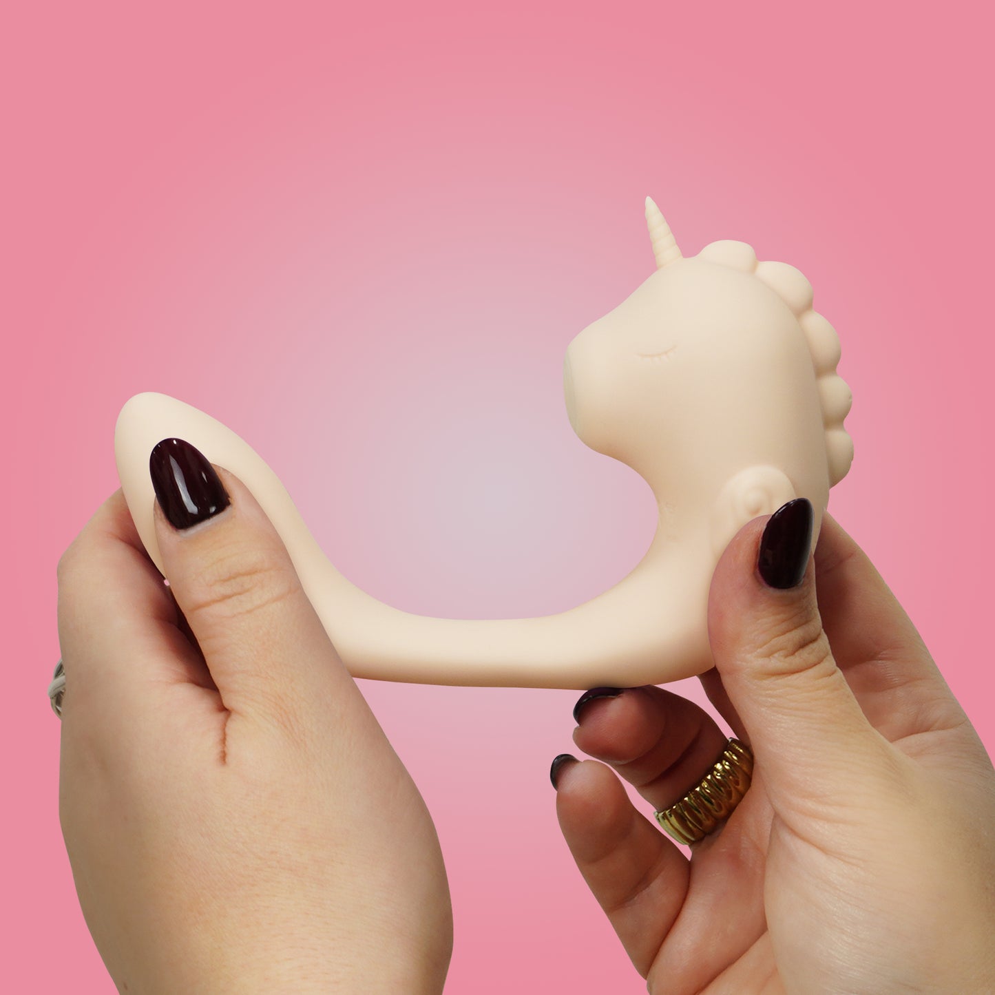 Coral Throb Unihorn C-Horse in stretched position side-view in hands on a pink background