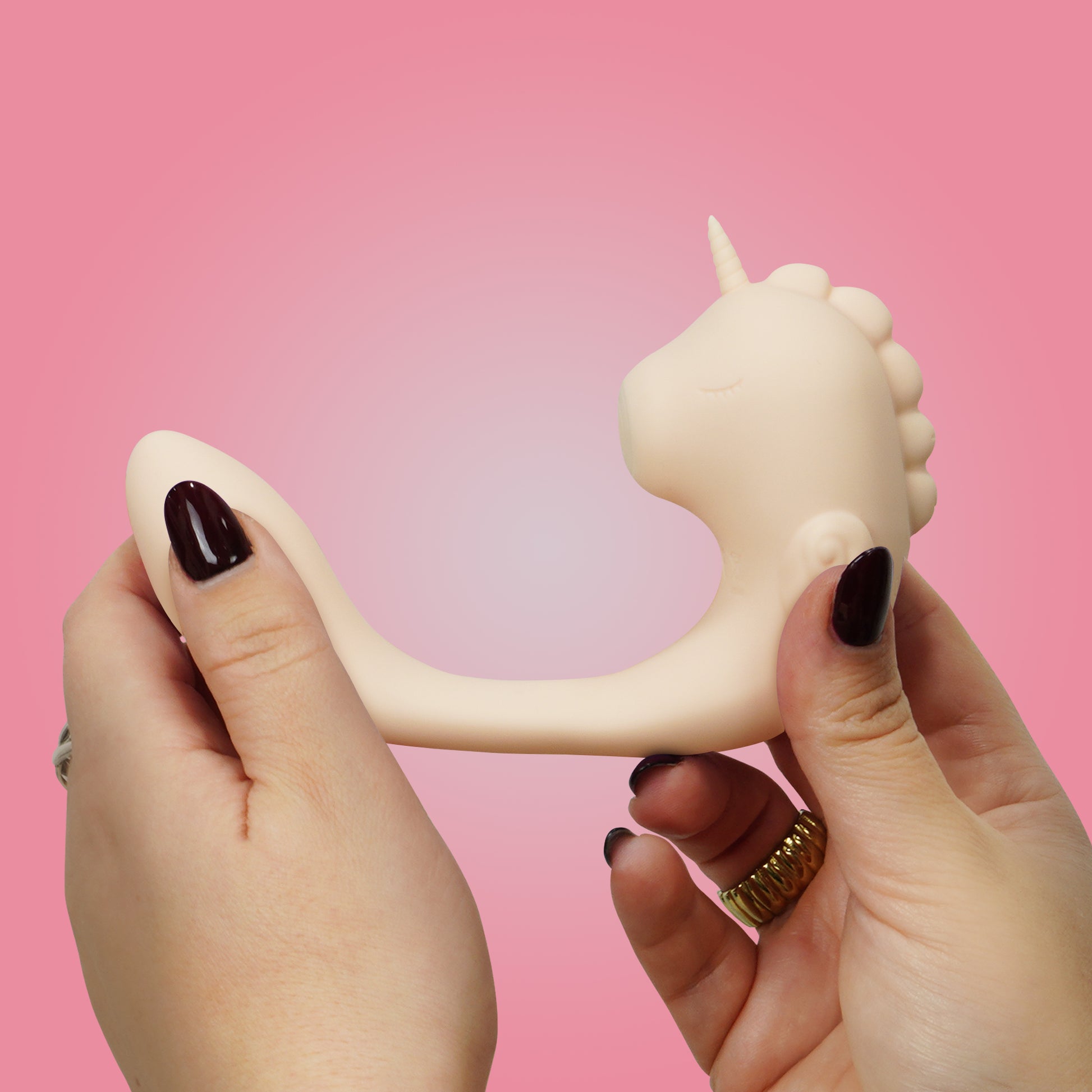 Coral Throb Unihorn C-Horse in stretched position side-view in hands on a pink background