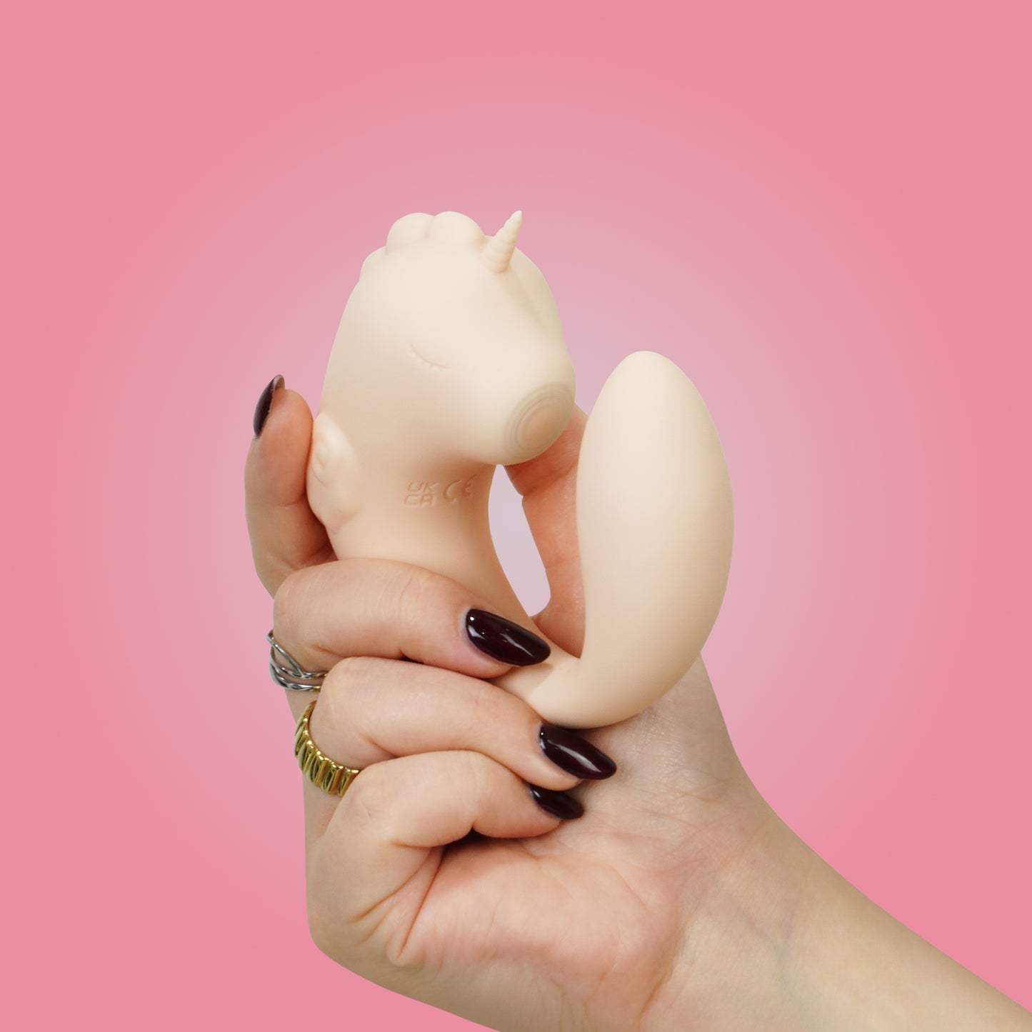 Coral Throb Unihorn C-Horse front in natural c-shaped position in hand on a pink background