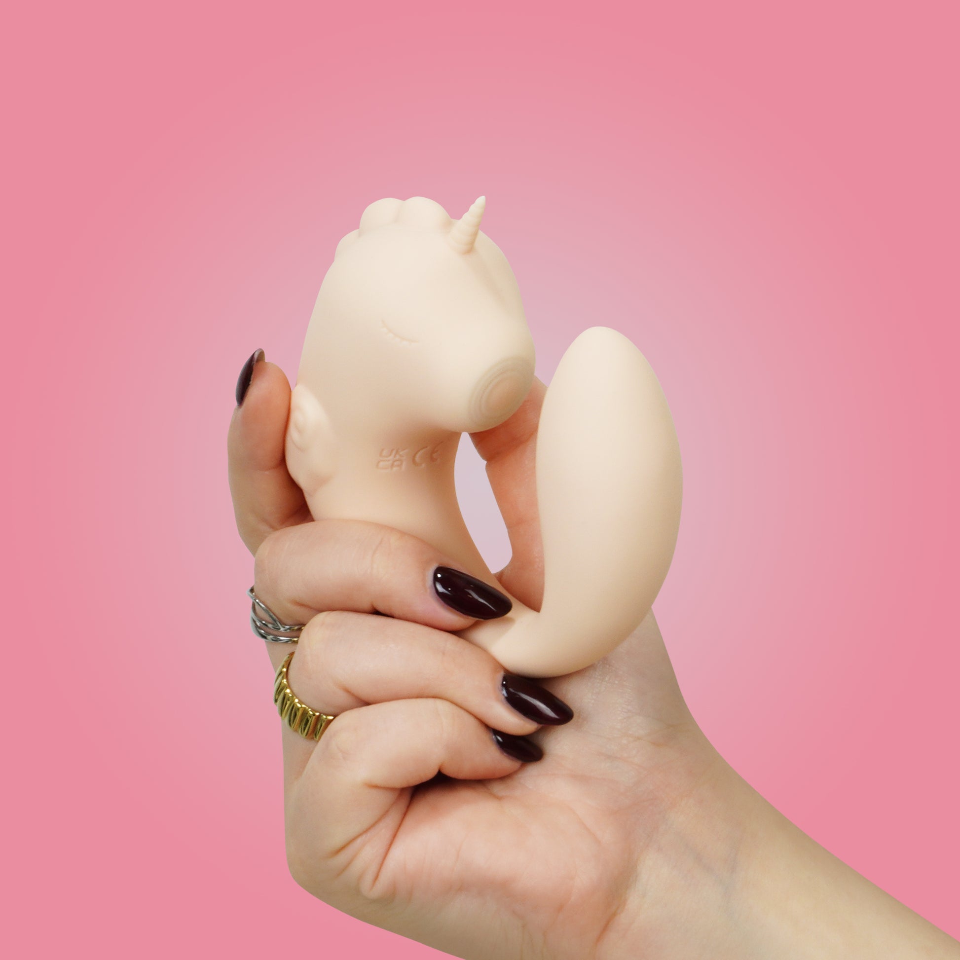 Coral Throb Unihorn C-Horse front in natural c-shaped position in hand on a pink background