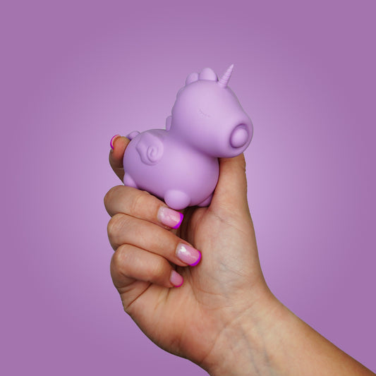 Hand holding the Karma Lilac unihorn vibrator on a bright purple background