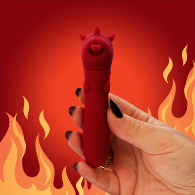 Hand holding Blaze Diablo bullet vibrator on a dark red background with orange flames at the bottom